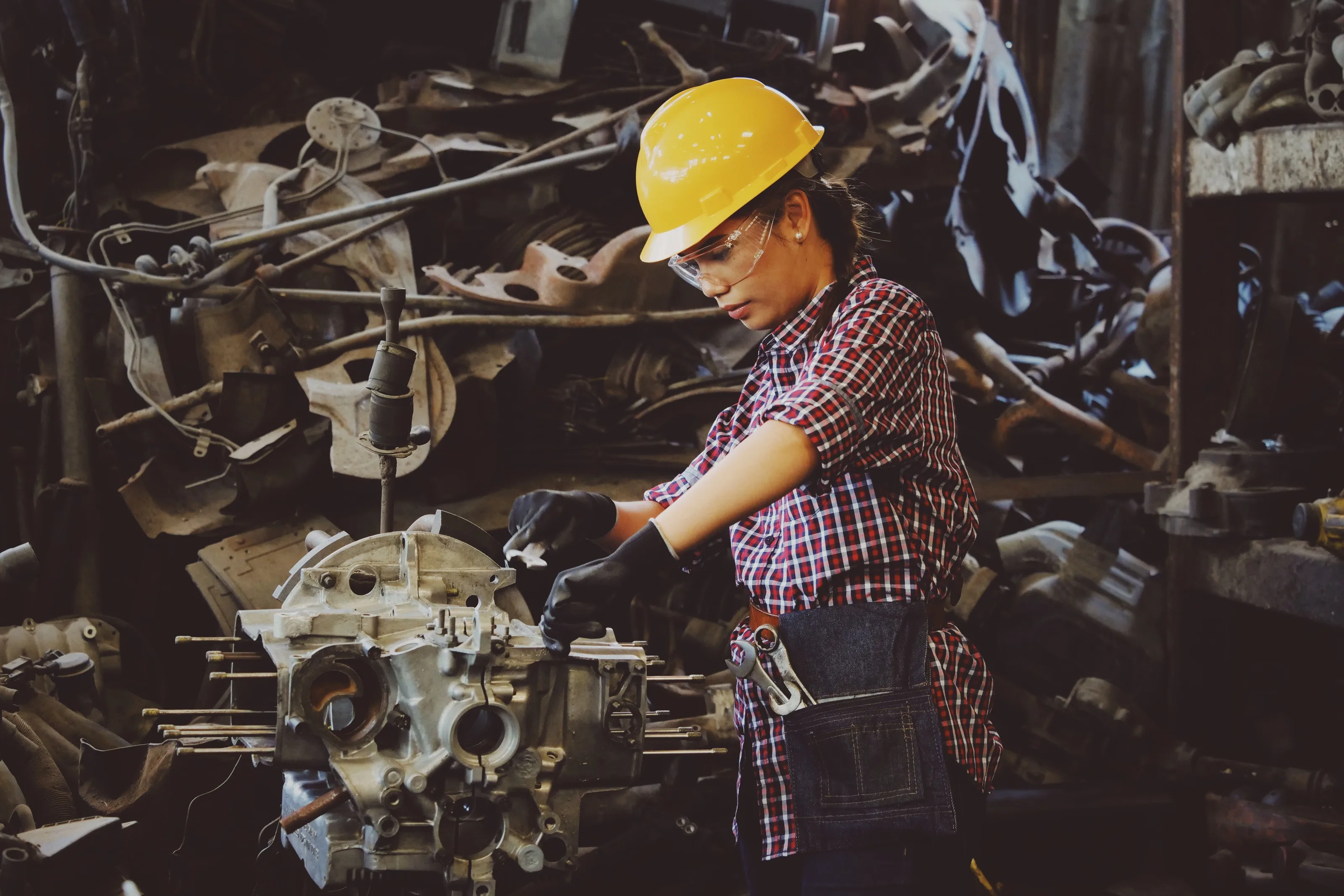 Una ingeniera con casco trabaja sobre una pieza de motor en un taller industrial