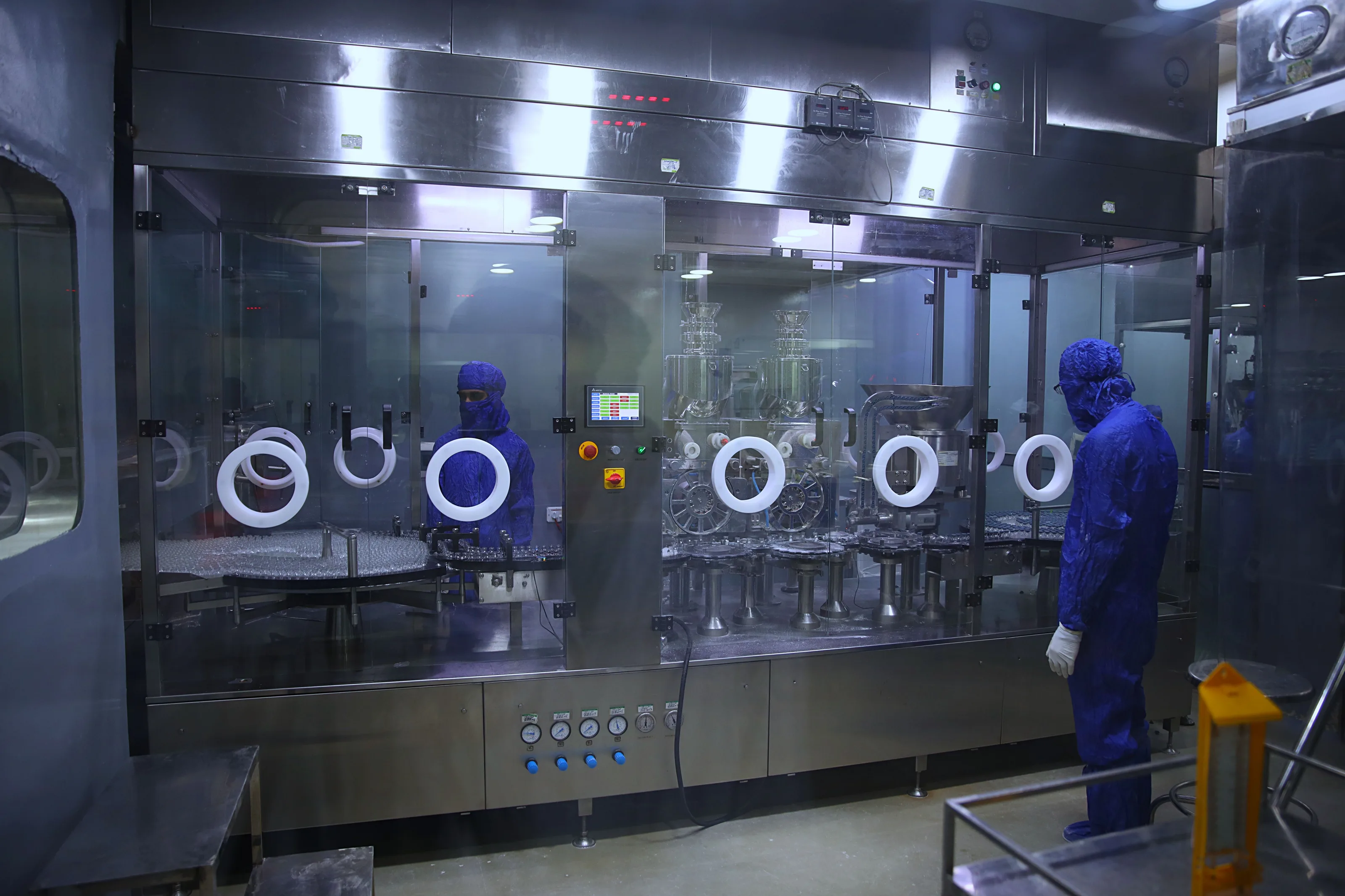 Personal con traje estéril dentro de una planta farmacéutica